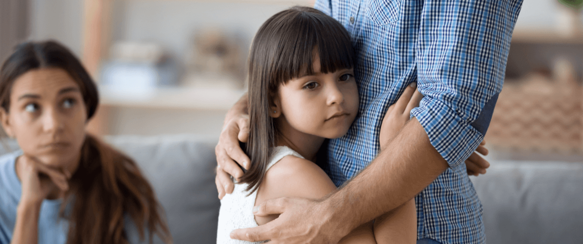 A young girl hugging her father while her mother sits nearby